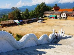 Una donna sale le scale del tempio rurale di Mae Hong Son decorato con un drago in stucco bianco, Thailandia - © icosha / Shutterstock.com