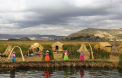 Donne in abiti tradizionali invitano i turisti a visitare le isole degli Uros sul lago Titicaca, Perù. Gli Uros sono una popolazione fuggita alle invasioni degli Inca. Sin da quell'epoca ...