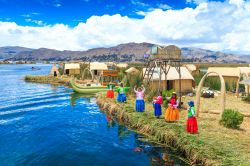 Donne in costume tradizionale accolgono i turisti sull'isola di Uros in Perù, lago Titicaca - © Pakhnyushchy / Shutterstock.com
