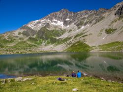 Due escurisonisti si riposano ai bordi di un lago dopo un trekking sulle montagne di Les Contamines, Francia.
