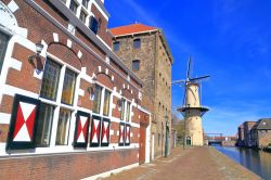 Edifici decorati si affacciano su un lato del canale di Schiedam, Olanda. Sullo sfondo un mulino a vento.

