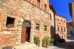 Edifici medievali in una strada soleggiata di Montepulciano, Toscana, Italia. La città è racchiusa da alte e imponenti mura.




