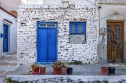 Facciata di una vecchia casa a Kythnos, Grecia. Pietra tinteggiata di bianco con porta e finestra azzurre per questa tradizionale abitazione dell'isola di Citno appartenente all'arcipelago ...
