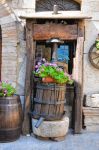 Fiori e vecchie botti in un vicolo del centro storico di San Gemini, Umbria, Italia.
