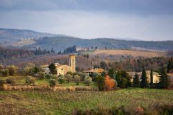 Foliage autunnale nei pressi di Barberino Val'd'Elsa, provincia di Firenze: vigneti e un'antica chiesa in pietra.

