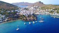 Foto con il drone del villaggio di Agia Marina sull'isola di Lores, Dodecaneso (Grecia). Di fronte al villaggio si trova una baia con sabbia soffice e acqua trasparente.

