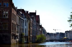 Il fascino senza tempo delle vecchie case affacciate sui canali di Gand, viste direttamente dall'acqua durante un giro turistico in barca.