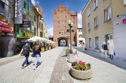 Gente a spasso in una via pedonale del centro di Olsztyn, Polonia. La strada termina nella Porta Superiore, frammento dell'antica cinta fortificata, l'unica ad esseersi mantenuta intatta ...