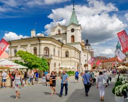 Gente a spasso nel centro di Lublino, Polonia, con la chiesa dello Spirito Santo in estate - © piotrbb / Shutterstock.com