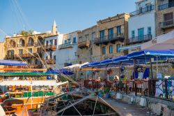 Gente in relax fra bar e ristoranti nel porto di Kyrenia, isola di Cipro. Questa pittoresca cittadina di mare è intrisa di profumi mediterranei; abbraccia il suo porto come se fosse disposta ...
