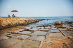 Gente in relax nei pressi di Zonqor Point Salt Pans a Marsascala, Malta. Si tratta di una serie di piscine naturali scolpite dalle onde del mare  - © Sun_Shine / Shutterstock.com