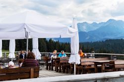 Gente in relax pranza in un caffé all'aperto con vista sui Tatra, Bukowina Tatrzanska (Polonia). Siamo nei pressi di Zakopane, località di villeggiatura alle pendici dei Tatra ...