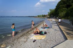 Gente in relax sulla spiaggia di Desenzano del Garda, provincia di Brescia, Lombardia. In prossimità del Lago di Garda ci sono quattro spiagge, tutte sassose: spiaggia Feltrinelli, di ...