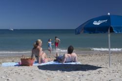 Gente in spiaggia a La Grande Motte, Camargue, Francia. Questa bella località situata fra Nimes e Montpellier, nella Piccola Camargue, possiede una decina di chilometri di costa per il ...