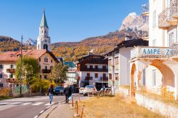 Gente in strada nel centro di Cortina d'Ampezzo, Veneto. Sullo sfondo, il campanile e le Alpi - © rbrechko / Shutterstock.com