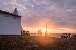 Gente osserva il tramonto alla Chapel of Sao Pedro dos Pescadores, isola di Fernando de Noronha, Pernambuco, Brasile - © Diego Grandi / Shutterstock.com