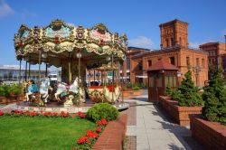 Una giostra per bambini nella piazza del centro commerciale Manufaktura a Lodz, Polonia. Qui sorgono complessi dedicati all'arte e allo shopping - © Mariola Anna S / Shutterstock.com ...