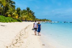 Una giovane coppia passeggia sulla spiaggia a Le Morne Brabant, Mont Choisy, Mauritius. Si tratta di una delle spiagge più belle dell'isola dove si trovano anche molti hotels e locali ...