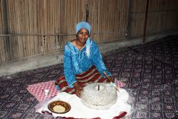 Una giovane donna beduina di Douz (Tunisia) indossa abiti tradizionali e macina il grano a mano - © meunierd / Shutterstock.com