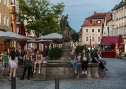 Giovani e turisti con abbigliamento estivo seduti su una fontana del centro storico di Bayreuth, Germania - © Werner Lerooy / Shutterstock.com