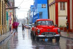 Iconico taxi rosso si riflette sulla strada bagnata di Holguin, Cuba. Siamo nella quarta più vasta città di Cuba - © alexsvirid / Shutterstock.com