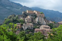 Le montagne avvolte dalle nuvole fanno da sfondo a Corte, storico borgo nell'entroterra della Corsica - tra vallate, ghiacciai e foreste di abeti e castagni, si trova Corte, storico borgo ...