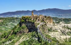 Il borgo laziale di Civita di Bagnoregio, il ponte che lo collega alla città e i calanchi del paesaggio. Si erge su di una rupe di tufo soggetta a frane e crolli. Per questò è ...