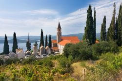 Il campanile di una chiesa a Orebic, Croazia, circondato da alberi di cipresso.

