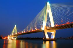 Il Century Bridge illuminato di notte a Haikou, Cina. Questo ponte strallato fu costruito per colelgare la parte principale della città all'isola di Haidian. Sorge circa 50 metri ...