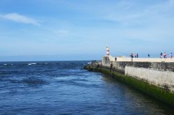 Il faro di segnalazione direzionale su un molo di Esposende con i pescatori, nord del Portogallo.

