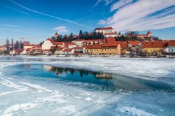 Il fiume Drava ghiacciato in inverno, Ptuj, Slovenia. Sullo sfondo, la cittadina circondata da una splendida natura.

