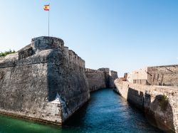 Il fossato navigabile del castello di Ceuta, Spagna. Su entrambi i lati delle mura sventolano le bandiere spagnole.



