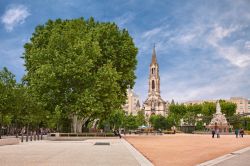 Il giardino di piazza Esplanade Charles-de-Gaulle a Nimes (Francia) con l'antica fontana Pradier e la chiesa di Santa Perpetua in stile neogotico.



