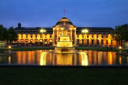 Il Kurhaus e il Bowling Green illuminati di sera, Wiesbaden, Germania. Il Bowling Green è un rettangolo allungato con prati e due piscine: il termine Bowling Green riporta al gioco con ...