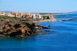 Il litorale roccioso di Cap d'Agde, Francia, con edifici residenziali sullo sfondo.
