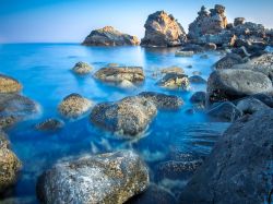 Il mare limpido tra gli scogli di Aci Trezza in Sicilia