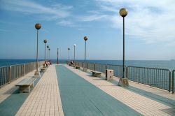 Il molo sulla spiaggia di Pietra Ligure, Riviera di Ponente. Dalla cima del molo molti vacanzieri si tuffano in acqua.
