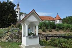 Una piccola edicola e sullo sfondo Il monastero di Olimje (Olimia) in Slovenia
