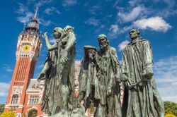 Il municipio fiammingo e neo-rinascimentale a Calais, Francia. In primo piano il gruppo scultoreo intitolato "I borghesi di Calais" realizzato da Auguste Rodin e installato in place ...