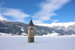 Il paesaggio incantato di Curon Venosta in inverno, con il campanile nel lago Resia, completamente congelato