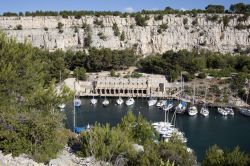 Il porto di Bandol con la costa rocciosa sullo sfondo, Francia. Uno splendido scorcio naturalistico fa da perfetta cornice al porticciolo di Bandol dove sono ormeggiate piccole imbarcazioni ...