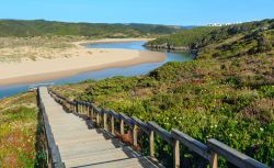Il sentiero in legno per la spiaggia di Amoreira e il fiume Aljezur fotografati in estate, Portogallo.


