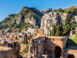 Il teatro greco di Taormina con l'Etna e il borgo di Castelmola sullo sfondo, Sicilia.
