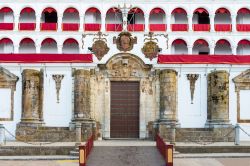 Ingresso della chiesa di Nostra Signora della Granada a Llerena, Spagna. Da notare gli stemmi e le decorazioni presenti nei pressi del portale e le arcate con i drappeggi rossi. 
