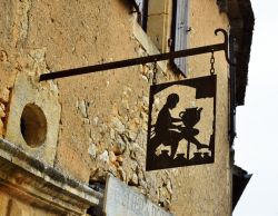 Insegna in ferro battuto di una bottega artigianale nel centro di Beynac-et-Cazenac, Francia.
