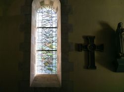 Interno dell'oratorio carolingio di Germigny-des-Pres, Francia, con una vetrata decorata e un crocifisso appeso al muro - © vvoe / Shutterstock.com