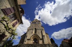 La chiesa di Beaulieu-sur-Dordogne (Francia) vista dal basso verso l'alto, in una giornata dal cielo azzurro e con le nuvole.
