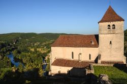 La chiesa di Saint-Cyr e Sainte-Julitte a Saint-Cirq-Lapopie, Occitania (Francia). Su un lato, il fiume Lot circondato da una vegetazione lussureggiante.



