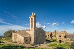 La chiesa restaurata nel borgo abbandonato di Occi, Lumio, Corsica. Sullo sfondo, le rovine degli altri edifici del villaggio.


