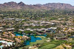 La cittadina di Scottsdale fotografata dall'alto, Arizona (USA): campi da golf, hotel di lusso e case con il monte Mummy sullo sfondo.

